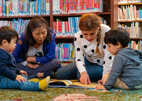 caregivers and babies reading on the floor