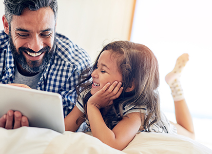 father and young daughter watch content from a tablet